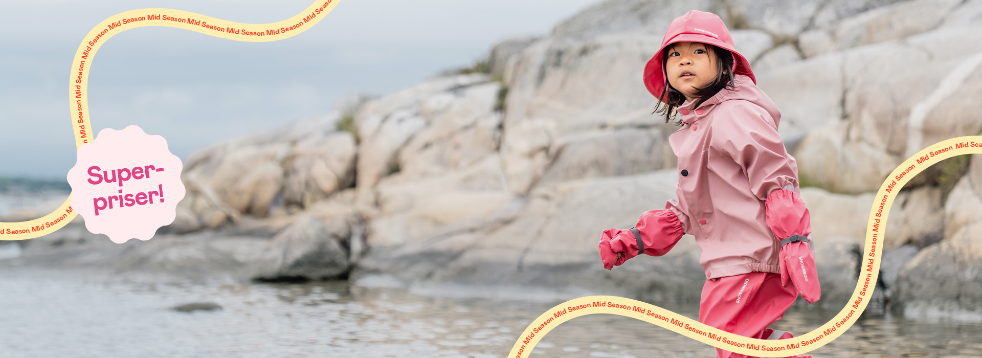 Barn i rosa regnkläder vid vatten, etikett “Super-priser!” nere till höger