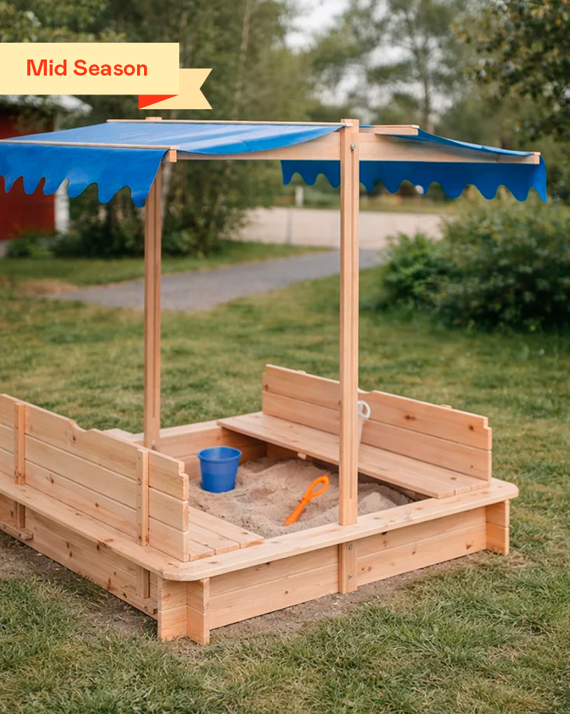 Träsandlåda med tak i trädgård, leksaker i sanden. Etikett: “Mid Season”.