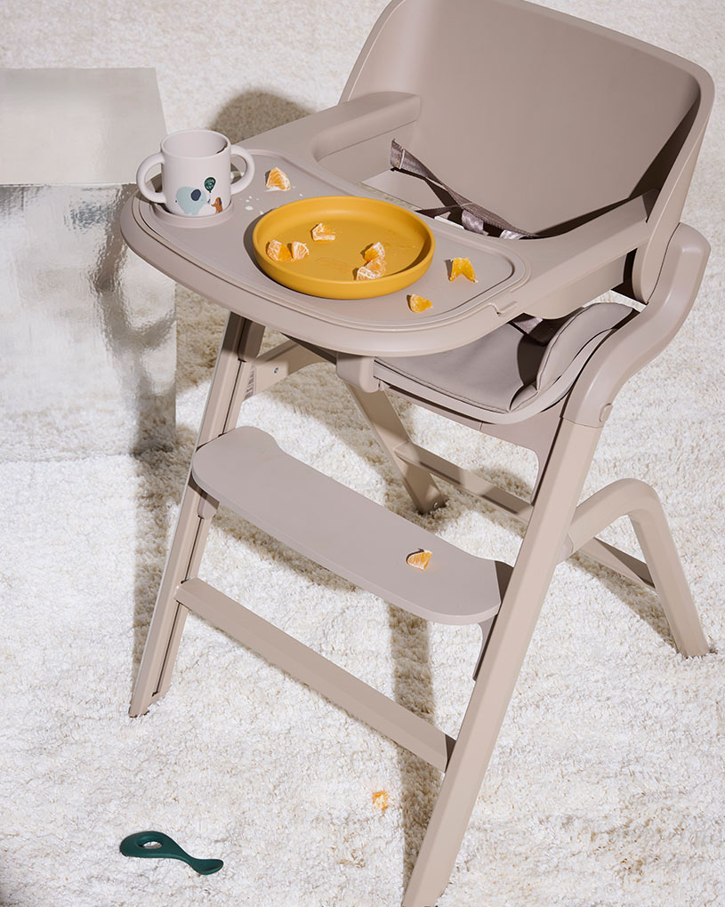 Matstol med en gul tallrik och en kopp med bitar av apelsin.